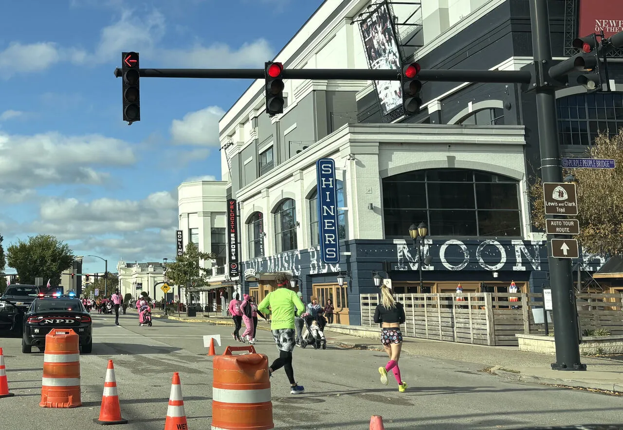 Walkers and runners in pink on a city street during Making Strides Against Breast Cancer of Greater Cincinnati and Northern Kentucky, with traffic cones and a police car along the route